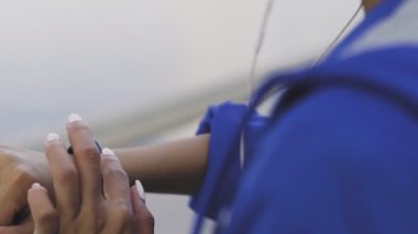 Koşmadan önce spor bilekliği takan kulaklıklı Afro-Amerikalı bir kadın.