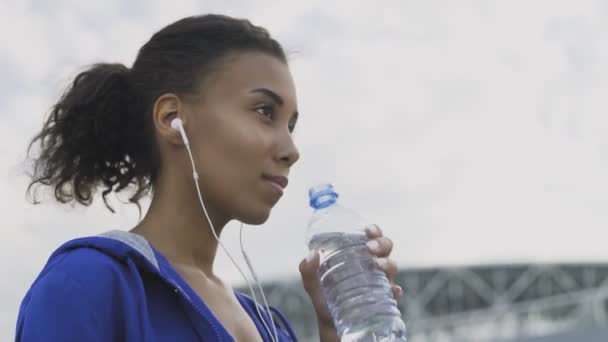 Mujer corredora afroamericana bebiendo agua después de correr. Retrato Fitness Mujer agua potable de la botella . — Vídeos de Stock