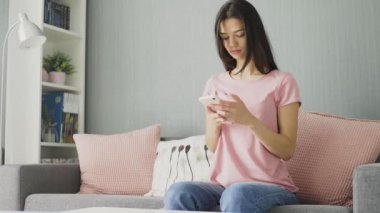 Evdeki kanepede otururken telefonunu kullanan genç, seksi esmer kadın..