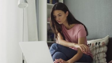Dizüstü bilgisayarla çalışan seksi kadın evde rahat oturuyor.