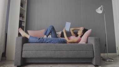 Güzel, genç bir kadın evinde kanepede uzanıp kurgu kitabı okumanın keyfini çıkarıyor. Güzel genç kız kanepede dinleniyor ve haftasonu evde yalnız başına kitap okumaktan zevk alıyor..