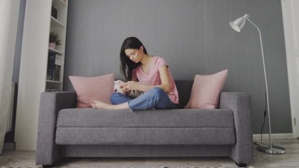 Mulher deixando smartphone e relaxante sentado em um sofá — Vídeo de Stock