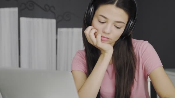 Krásná žena ve sluchátku poslech hudby z notebooku, zatímco sedí v ložnici — Stock video