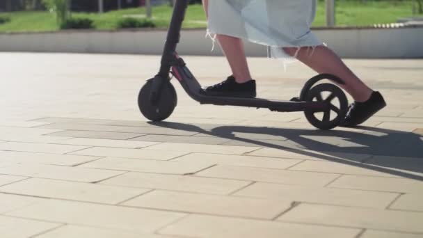 Jonge vrouw bestuurder van elektrische scooter in het stadspark. ecologisch vervoer. — Stockvideo