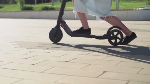 Junge Fahrerin eines Elektrorollers im Stadtpark. ökologischer Verkehr. — Stockvideo