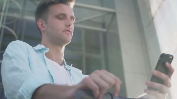 Закрити Чоловік використовує смартфон після їзди на електричному скутері — стокове відео