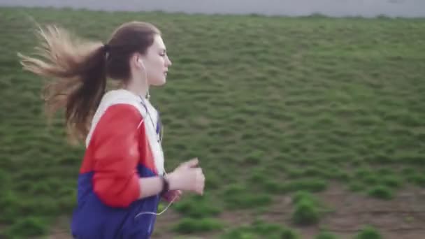 Atletische fitness vrouw met koptelefoon draait in de stad — Stockvideo