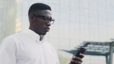 Beyaz gömlek giyen şık Afro-Amerikan işadamı ofisin dışında kahve içiyor.