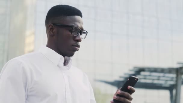 Stijlvolle Afro-Amerikaanse zakenman in wit shirt drinkt koffie buiten bij kantoor — Stockvideo