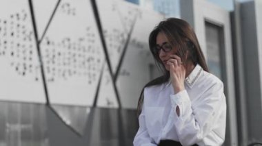 Akıllı telefondan konuşan şık bir kadın. Arka plandaki modern bina