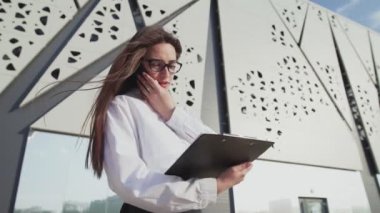 Kadın sekreter patronla akıllı telefondan konuşuyor ve belgelerimizi kontrol ediyor.