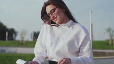 Kadın sekreter patronla akıllı telefondan konuşuyor ve belgelerimizi kontrol ediyor.