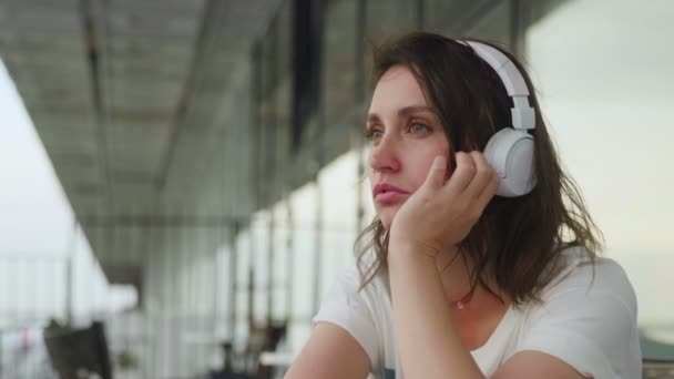 Mulher bonita ouvindo emocionalmente música em fones de ouvido com smartphone — Vídeo de Stock