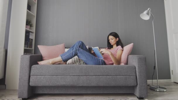 Sleepy woman lying on couch reading boring book at home. College girl student study in sofa looking textbook feel bored — Stock Video