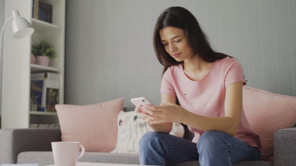 Close up da jovem mulher branca atraente tocando, rolando e digitando no smartphone — Vídeo de Stock