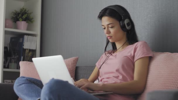 Freelancer jovem sério trabalhando em freelancer de casa digitar e-mail no laptop, menina focada usando o computador para estudar on-line em casa sentado no sofá — Vídeo de Stock