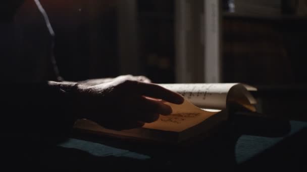 Monje está leyendo un viejo libro en la oscuridad — Vídeos de Stock