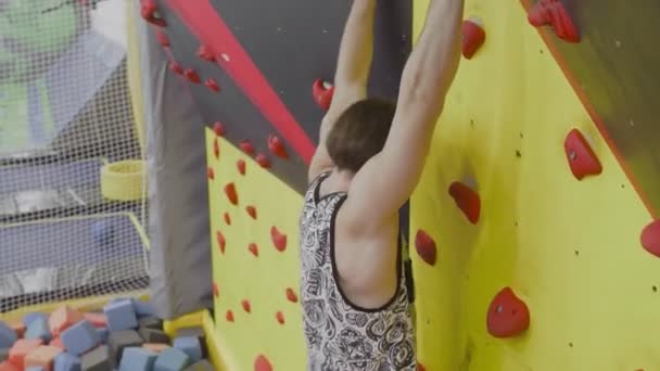 Hombre moviéndose en un muro de escalada — Vídeo de stock