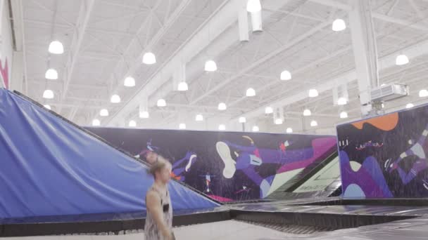 Sportoló akrobatikus elemeket ad elő egy trambulinon. — Stock videók
