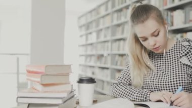 Kadın kütüphanede kağıda yazıyor.