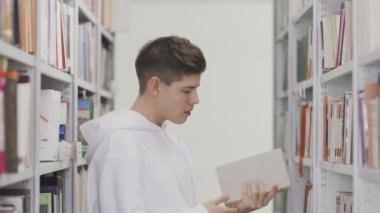 Kütüphanedeki kitaplıktan kitap alan öğrenci