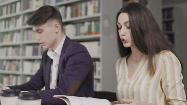 Två kaukasiska universitetsstudenter förbereder sig för examen i biblioteket — Stockvideo