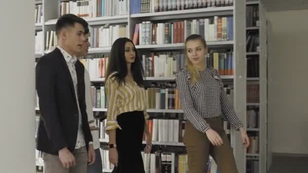 Jóvenes estudiantes caminando en la biblioteca universitaria . — Vídeos de Stock