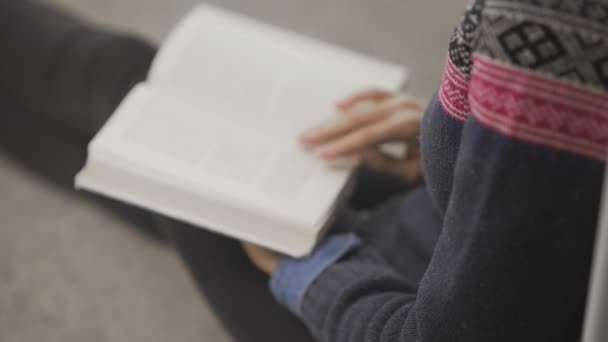 Über-die-Schulter-Blick einer jungen afrikanisch-amerikanischen Frau liest Buch, das auf dem Boden in der Universitätsbibliothek sitzt. — Stockvideo