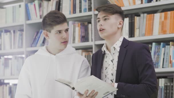 Jóvenes estudiantes con libros preparándose para el examen en la biblioteca — Vídeos de Stock