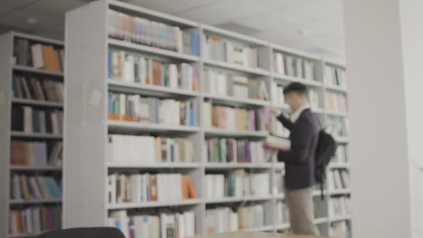 Um estudante veio à biblioteca e começou a ler — Vídeo de Stock