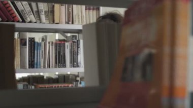 Genç Afrikalı Amerikalı öğrenci kütüphanede kitap arıyor.