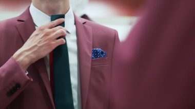 Zarif kırmızı takım elbiseli bir erkek kravatını seçer.