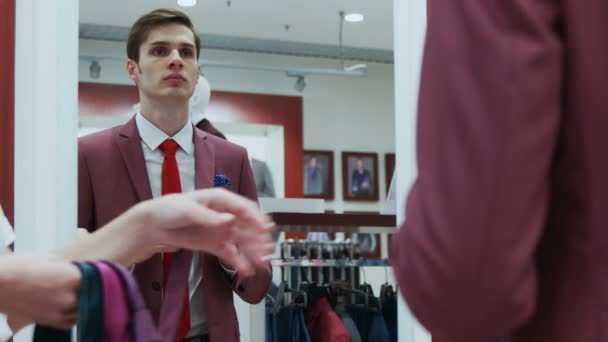 Hombre vestido con elegante traje rojo mira al espejo y elige su corbata — Vídeos de Stock