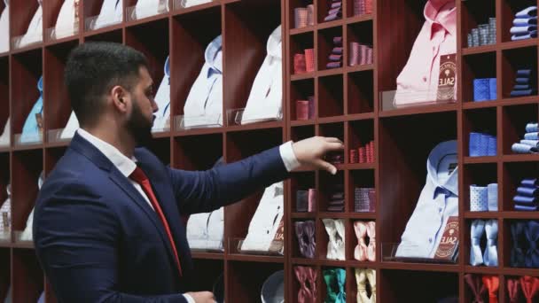 Biznesmen w niebieskiej kurtce wybiera krawat w sklepie — Wideo stockowe