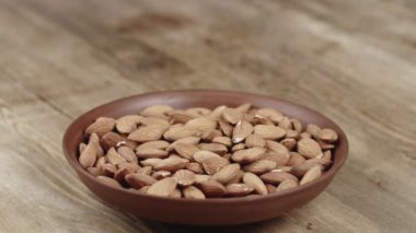 Kadın, yemek için kasesinden bir avuç badem topluyor. Sol tarafıma fındık kaçtı.