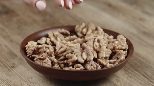 Vrouw pakt een enkele walnoot, om op te eten, van haar schaal. Nam een moer aan de rechterkant — Stockvideo