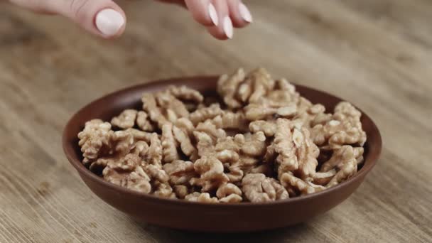 Vrouw pakt een handvol walnoot, om op te eten, van haar schaal. Nam een moer aan de rechterkant — Stockvideo