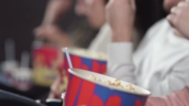 Sinemadaki arkadaşlar film izliyor kola içiyor ve patlamış mısır yiyorlar..