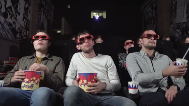 Três amigos estão assistindo um filme e comendo pipocas — Vídeo de Stock