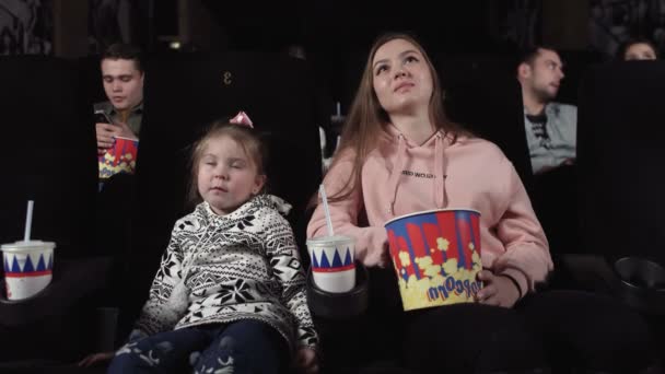 Маленькая девочка и мама смотрят кино и едят попкорн — стоковое видео