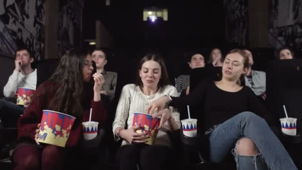 Tres amigas guapas viendo una película en el cine. Hombre insatisfecho con las niñas hablando en voz alta — Vídeo de stock