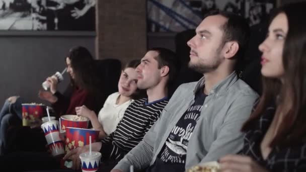 Glada vänner som tittar på film på teatern. Par och andra människor äter popcorn och dricker läsk medan de tittar på film på bio. — Stockvideo