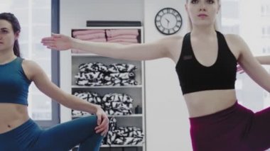 Güzel genç kadınların Dolly hareketi hafif çatı katı tarzı sağlık merkezinde yoga asanalarını esnetme kompleksi yapıyor..