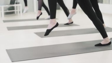 Genç kadınlar spor kulübünde havacılık yogası yapıyorlar. Kadınlar bacaklarını açar.