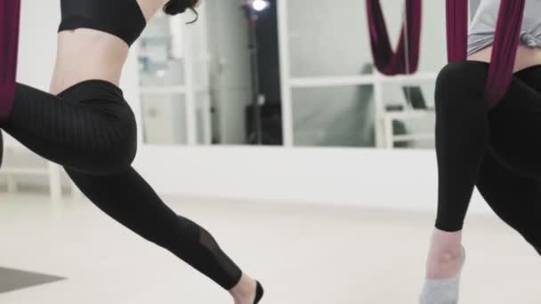 Flexible Frauen dehnen Gliedmaßen mit Unterstützung auf rotem Lufttuch. — Stockvideo