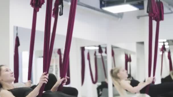 Les belles femmes planent dans l'hamac dans l'espace aérien du studio à l'intérieur . — Video