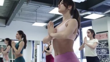 Yoga yapan bir grup insan fitness stüdyosunda yoga yapıyor.