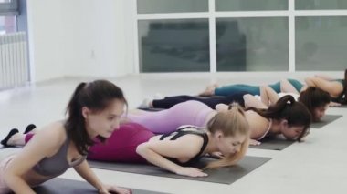 Sporcu kadınlar yoga pozisyonunda geriliyor.