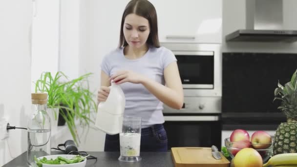 Bella giovane donna sta facendo il frullato di cocktail con latte nel frullatore — Video Stock