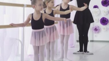 Küçük kızlar klasik bale dersi alıyor. Resim atölyesinde öğretmenle bacak hareketleri öğreniyorlar..